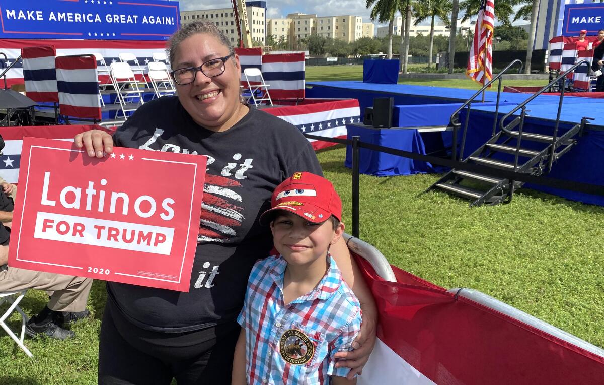 Amera Franklin holds a "Latinos for Trump" sign with her 7-year-old son at a park.