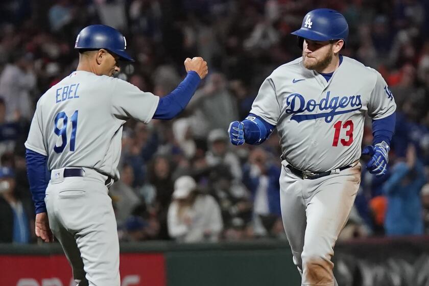 Los Angeles Dodgers' Max Muncy (13) is congratulated by third base coach Dino Ebel (91) after hitting a grand slam.