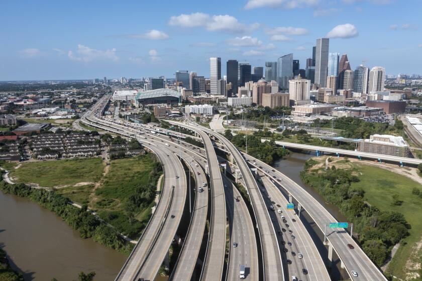 Houston, CA - August 18: An aerial view where Interstate 69 crosses Buffalo Bayou northeast of downtown Houston, next to the Clayton Homes, shown at left, a Houston Housing Authority complex that would be demolished if current plans for redevelopment of Interstate 45 proceeds as planned Wednesday, Aug. 18, 2021. In the mid-20th century, the federal interstate highway program was notorious for building new roads through Black and Latino neighborhoods, a practice that displaced hundreds of thousands of families and ruined longstanding communities. Many of these episodes are now seen as a stain on U.S. housing and transportation policy because of how they devastated already under-resourced and segregated neighborhoods. (Allen J. Schaben / Los Angeles Times)