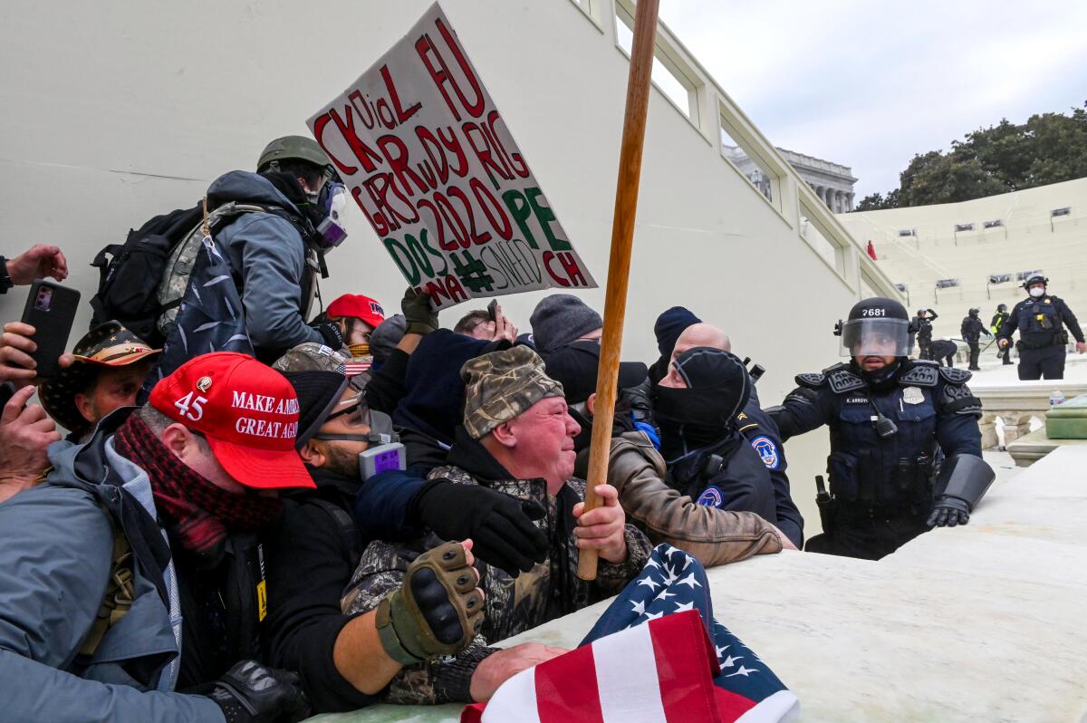 Supporters of then-President Trump carrying signs clash with police at the U.S. Capitol on Jan. 6.