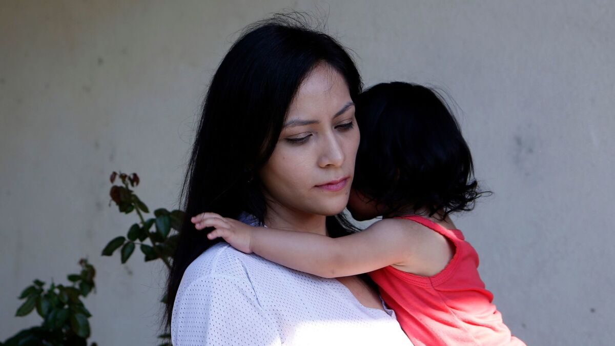 Venecia Yanez holds her 1-year-old daughter Mia outside their home in Paramount. Air quality regulators have detected a potent cancer-causing metal in the city at 350 times normal levels.