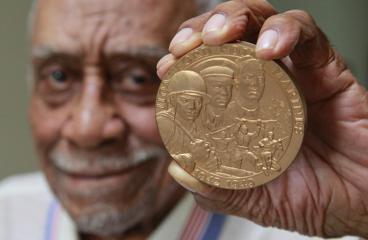 Robert L. Moore, seen here in 2019, holds a replica of the Montford Point Marine Congressional Gold Medal.
