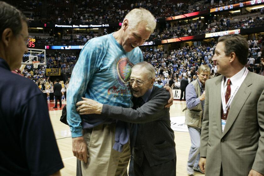 Legendary UCLA basketball coach John R. Wooden, right, hugs his former player Bill Walton.