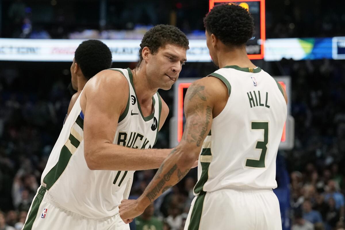 Milwaukee Bucks center Brook Lopez (11) is congratulated by guard George Hill (3) after the team's NBA basketball game against the Dallas Mavericks in Dallas, Friday, Dec. 9, 2022. The Bucks won 106-105. (AP Photo/LM Otero)