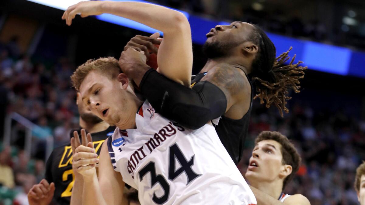 Saint Mary's center Jock Landale (34) and Virginia Commonwealth forward Mo Alie-Cox get tangled while battling for rebounding position during the first half.