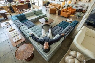 HOLLYWOOD, CA-MAY 8, 2023: Jason Potter, owner of Den, a store specializing in the sale and restoration of 20th century furniture and design, is photographed on a mahjong sofa produced by Roche Bobois. The material is a mix of velvets, boucle and mohair. (Mel Melcon / Los Angeles Times)