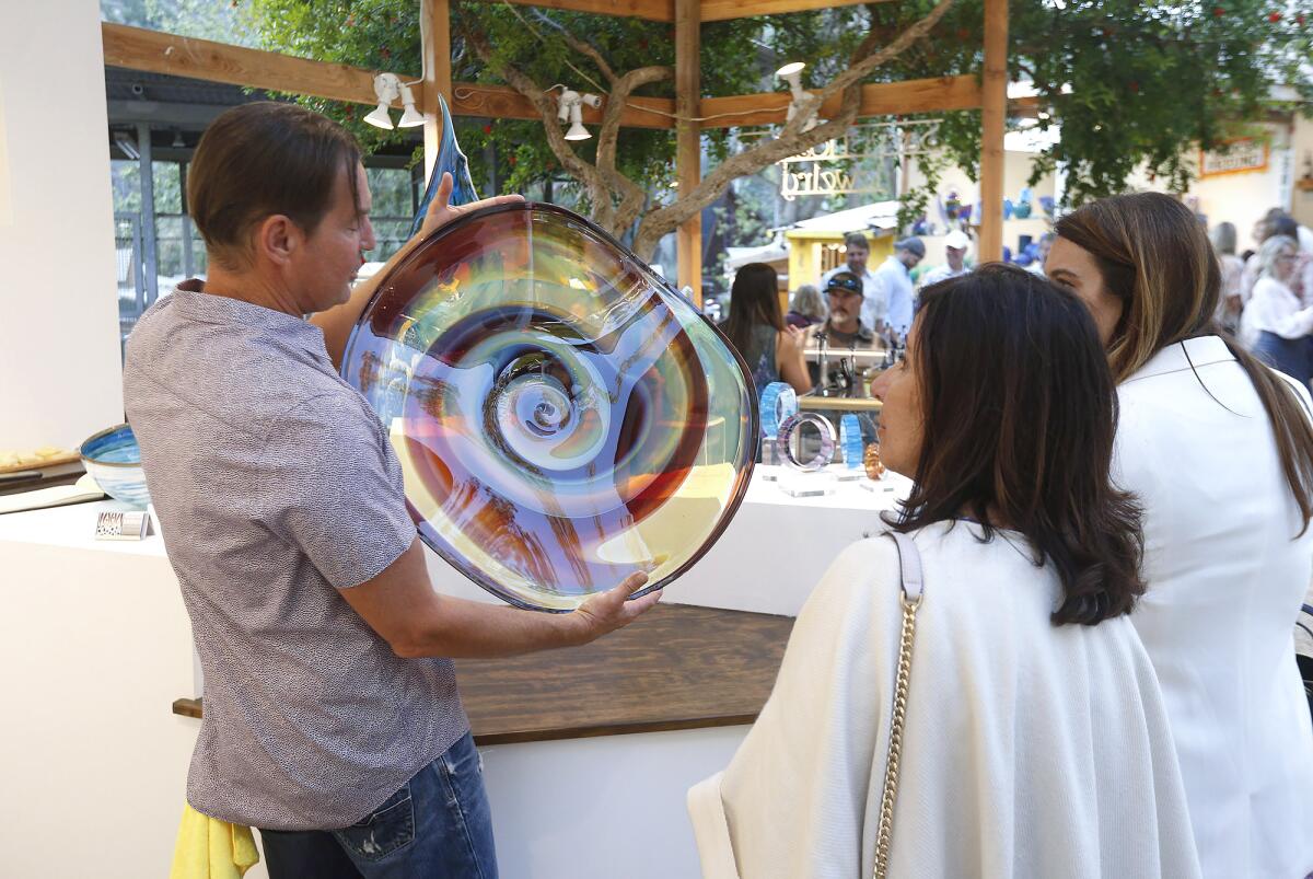 Glass artist Marcus Thesing shows guests a piece during the Sawdust Art Festival's locals preview night on Tuesday.