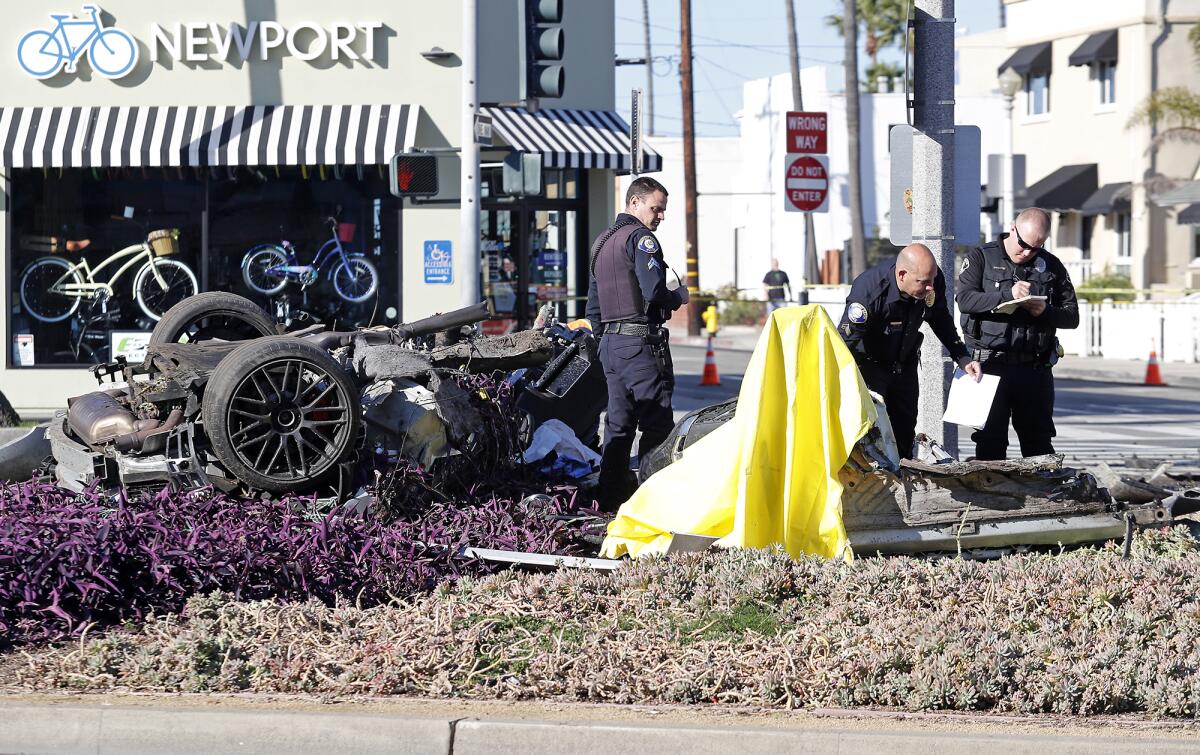 Newport Beach police investigate the scene of a deadly crash Tuesday morning near 23rd Street and Balboa Boulevard. A man was killed and a woman injured when a 2016 Mercedes-AMG hit a tree and split in half at the end of a high-speed police pursuit.