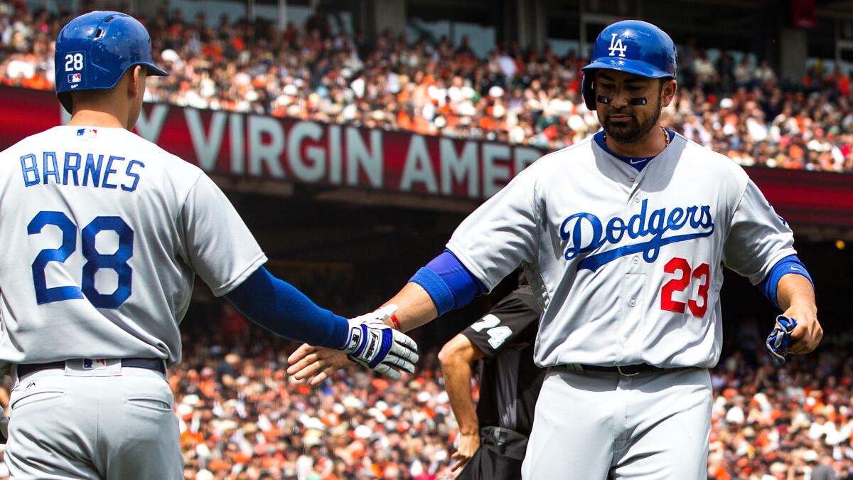Adrian Gonzalez (23) is congratulated by Austin Barnes after scoring against the Giants in the second inning, when the Dodgers extended the inning by winning a challenge at second base.