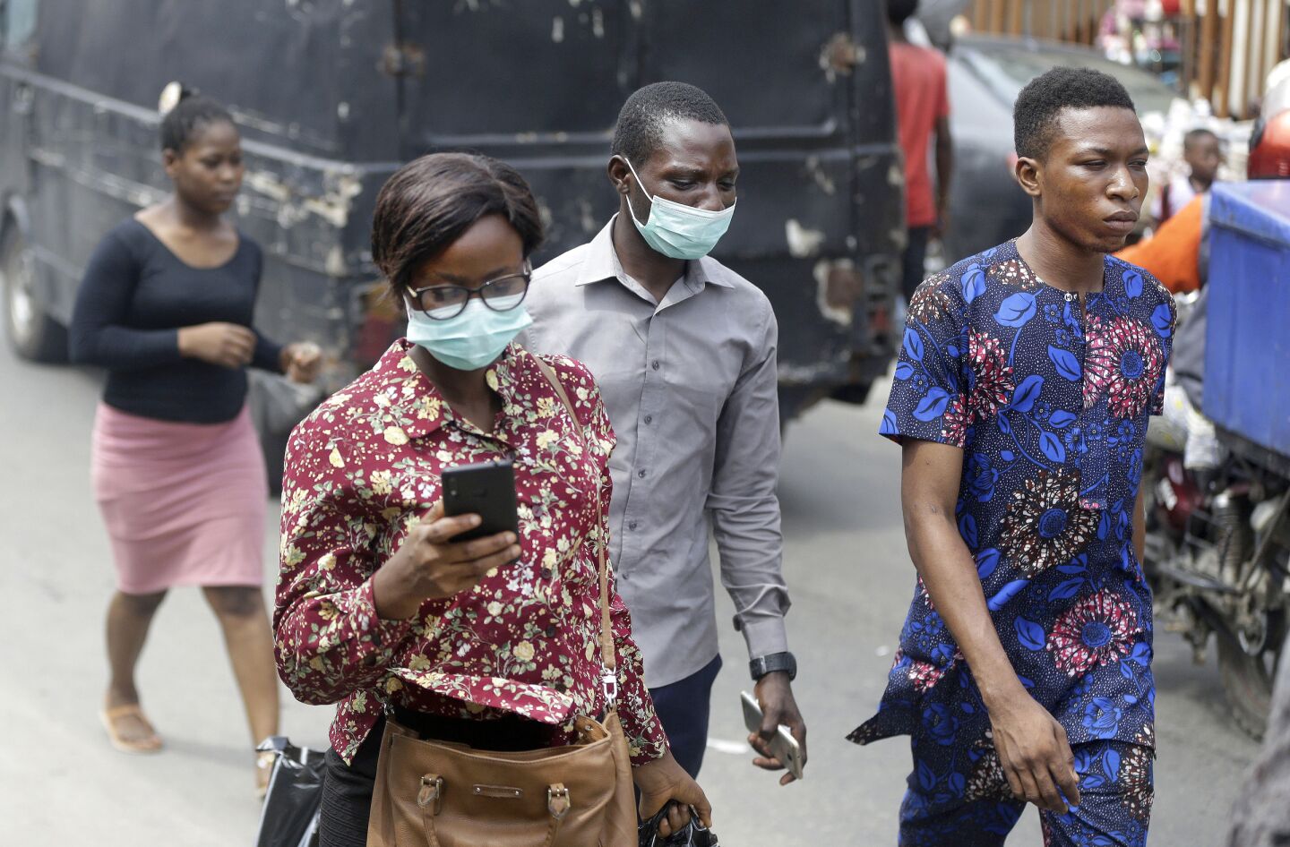 Nigeria: People wearing face masks walk through a busy market in Lagos, Nigeria.