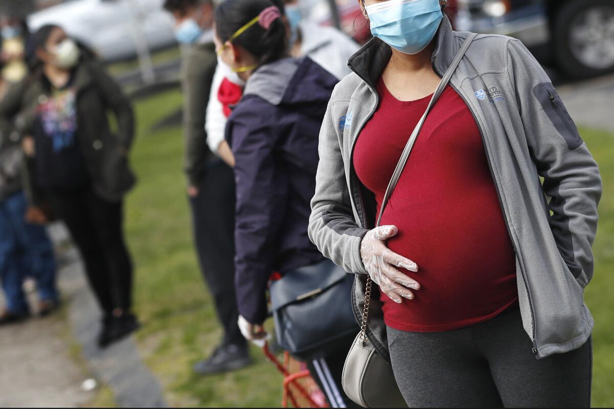 A woman's hand touches her pregnant belly.