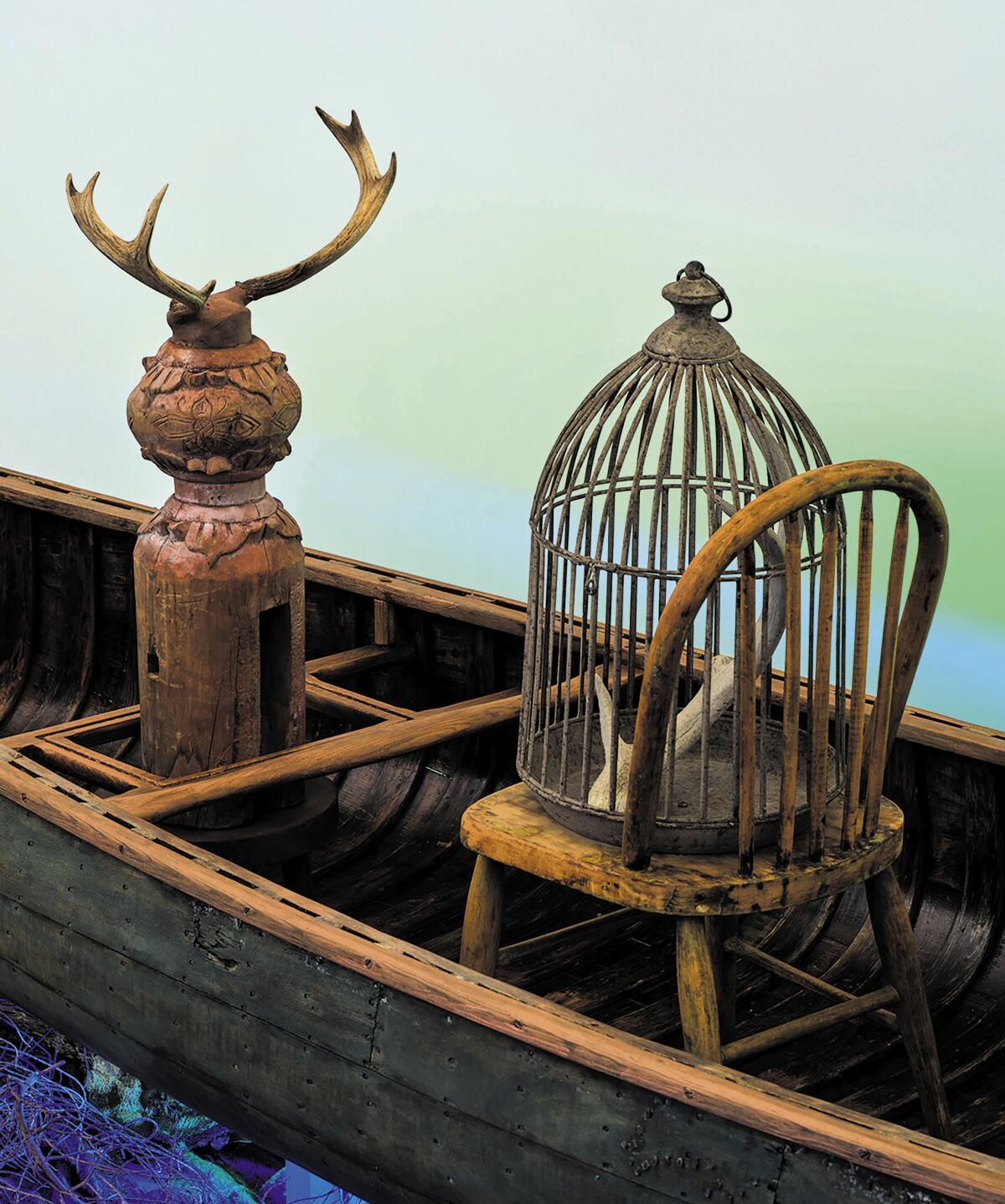 A chair, birdcage and antlers sitting in a canoe.