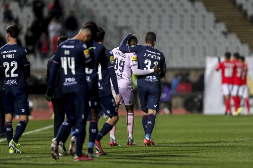 Belenenses' Joao Monteiro, center right, a goalkeeper who had to start as a field player, leaves the pitch with goalkeeper Alvaro Ramalho at the end of the Portuguese Primeira Liga soccer match between Belenenses SAD and SL Benfica, Saturday, Nov. 27, 2021. Belenenses SAD started the match with only nine players due to a coronavirus outbreak. Portuguese health authorities on Monday, Nov. 29, 2021, identified 13 cases of omicron, the new coronavirus variant spreading fast globally, among members of Belenenses SAD. (AP Photo/Pedro Rocha)