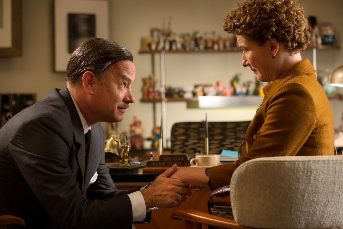 A man in a suit holds a woman's hand  in the movie "Saving Mr. Banks."