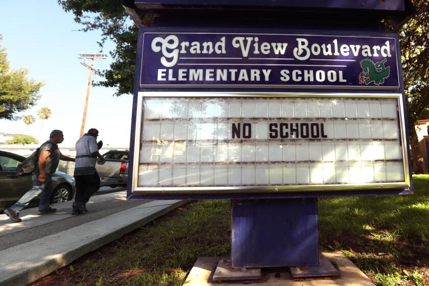 MAR VISTA, CA - JULY 13, 2020 - - Pedestrians walk past the Grand View Boulevard Elementary School with a marquee that still reads, "No School," in Mar Vista on July 13, 2020. Los Angeles campuses will not reopen for classes on Aug. 18, and the nation's second-largest school system will continue with online learning until further notice, because of the worsening coronavirus surge, Supt. Austin Beutner announced Monday. "Let me be crystal clear," Beutner said in an interview with The Times. "We all know the best place for students to learn is in a school setting." But, he said, "We're going in the wrong direction. And as much as we want to be back at schools and have students back at schools - can't do it until it's safe and appropriate." (Genaro Molina / Los Angeles Times)