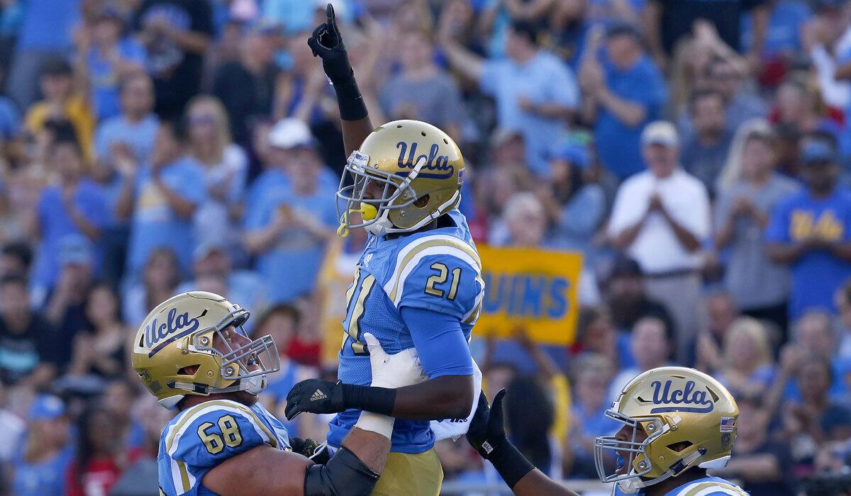 UCLA's Mossi Johnson, center, celebrates with teammates Conor McDermott, left, and Jalen Starks after scoring a touchdown Sept. 10 against the University of Nevada, Las Vegas.