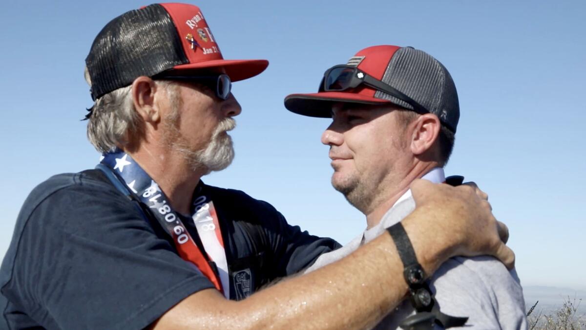 Will Mitchell, left, whose firefighter son Ryan took his own life in 2017, hugs Jason McMillan, who fought fires alongside Ryan Mitchell and recently took part in a trauma retreat to deal with his anxiety and depression.