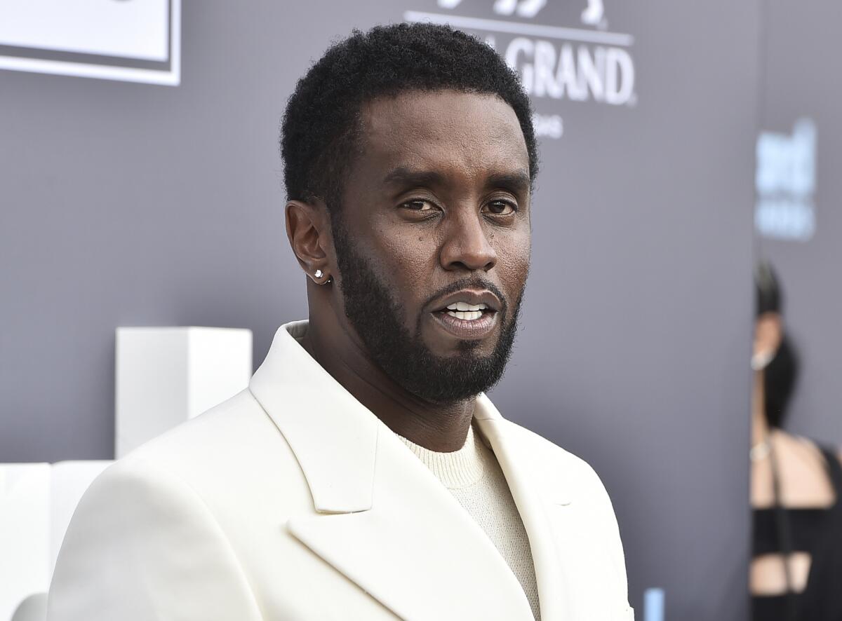 Sean "Diddy" Combs poses at an event in a cream suit.