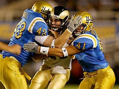 UCLAs Dave Ball, left, and Spencer Havner combine to put the squeeze on Colorado State quarterback Bradlee Van Pelt in the first half at the Rose Bowl.