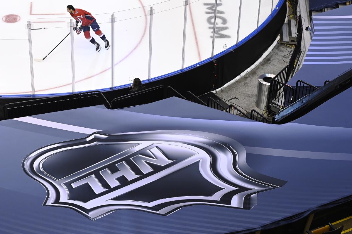 An NHL logo is shown as Washington Capitals defenseman Brenden Dillon (4) skates prior to NHL Eastern Conference Stanley Cup playoff hockey action against the New York Islanders in Toronto, Friday, Aug. 14, 2020. The NHL is providing its playoff teams a few tastes of home in their respective hub cities. Teams are hearing their pre-game warm-up music, goal songs and national anthem performers. Crowd noise is being piped in and new camera angles have been added for a TV audience. (Nathan Denette/The Canadian Press via AP)