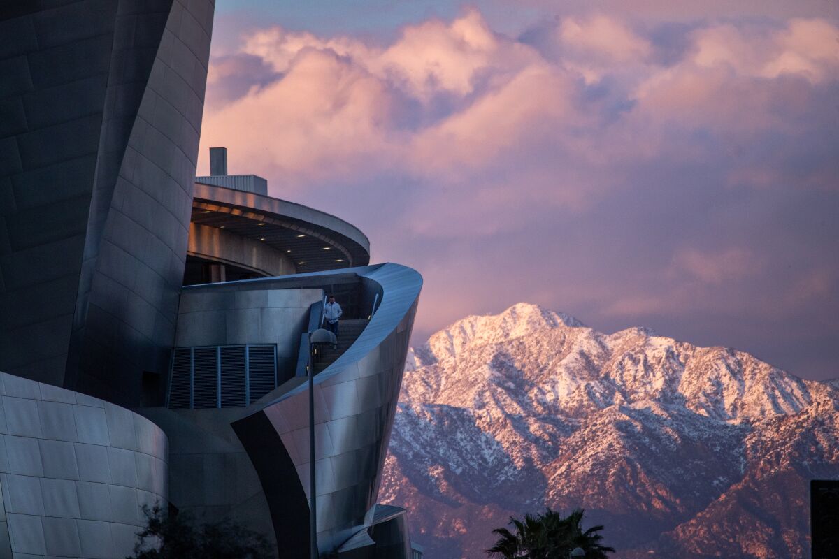 The Walt Disney Concert Hall in downtown Los Angeles, looking over the snow-capped San Gabriel mountains.