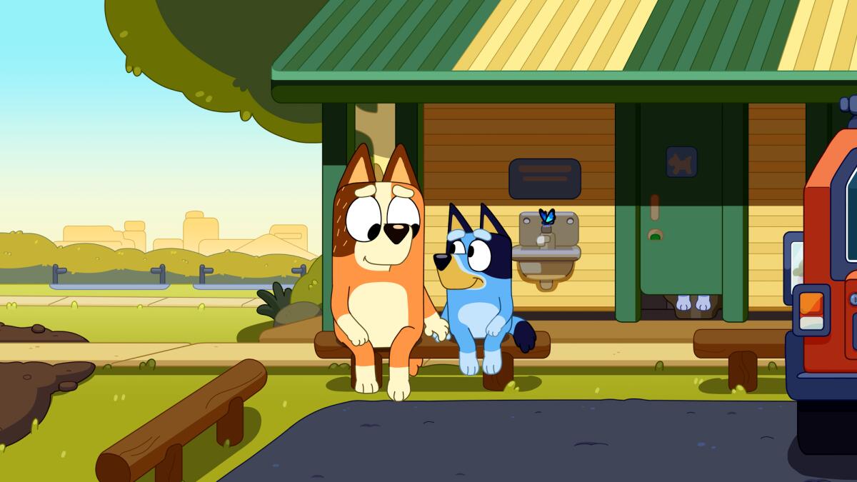 Two animated dogs sit outside a restroom.
