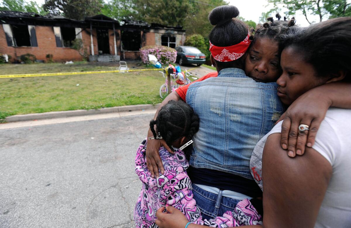 Family members and neighbors console each other following a house fire that killed four children and their mother in Newnan, Ga. The children's older sister, 11, was the only survivor.