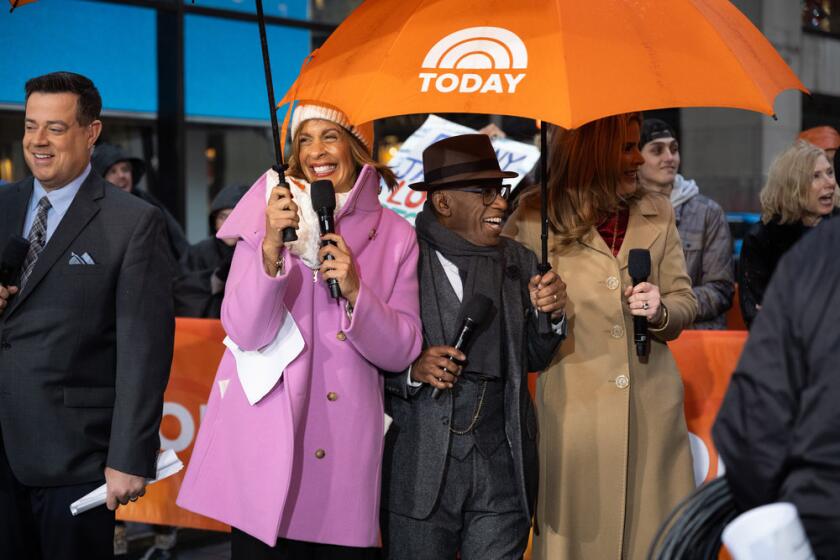 Carson Daly stands next to Hoda Kotb, Al Roker and Jenna Bush Hager huddling under an orange 'Today' umbrella.