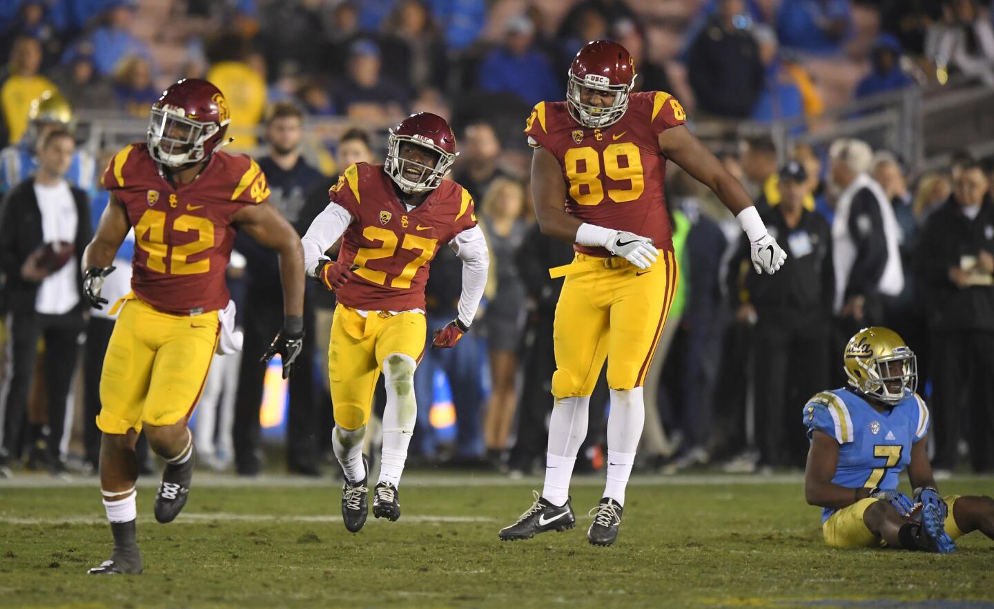 Southern California defensive back Ajene Harris, second from left, celebrates along with linebacker Uchenna Nwosu, left, and defensive end Christian Rector, second from right, after tackling UCLA wide receiver Darren Andrews, right, one yard short of a first down on fourth down during the second half of an NCAA college football game.