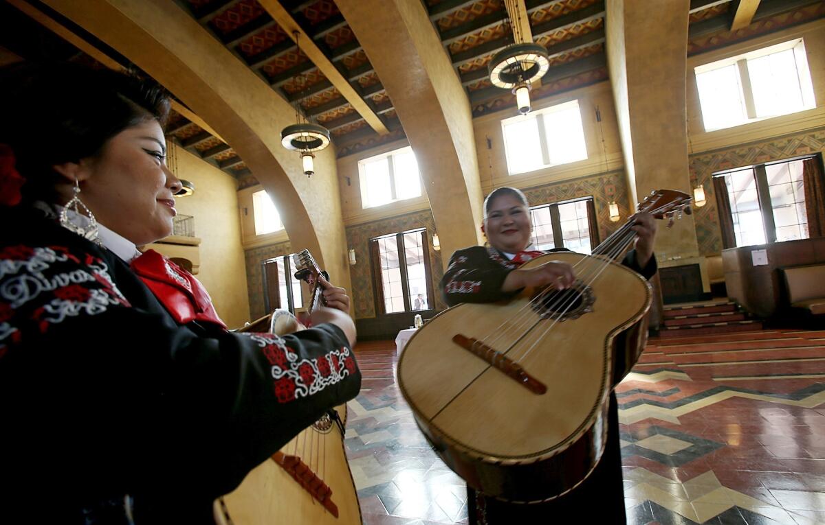 Daniela Gutierrez and Wendy Alarcon, members of Mariachi Diva, warm up before performing at the launch of Covered California, the state's Affordable Care Act marketplace, at Union Station in Los Angeles on Tuesday.