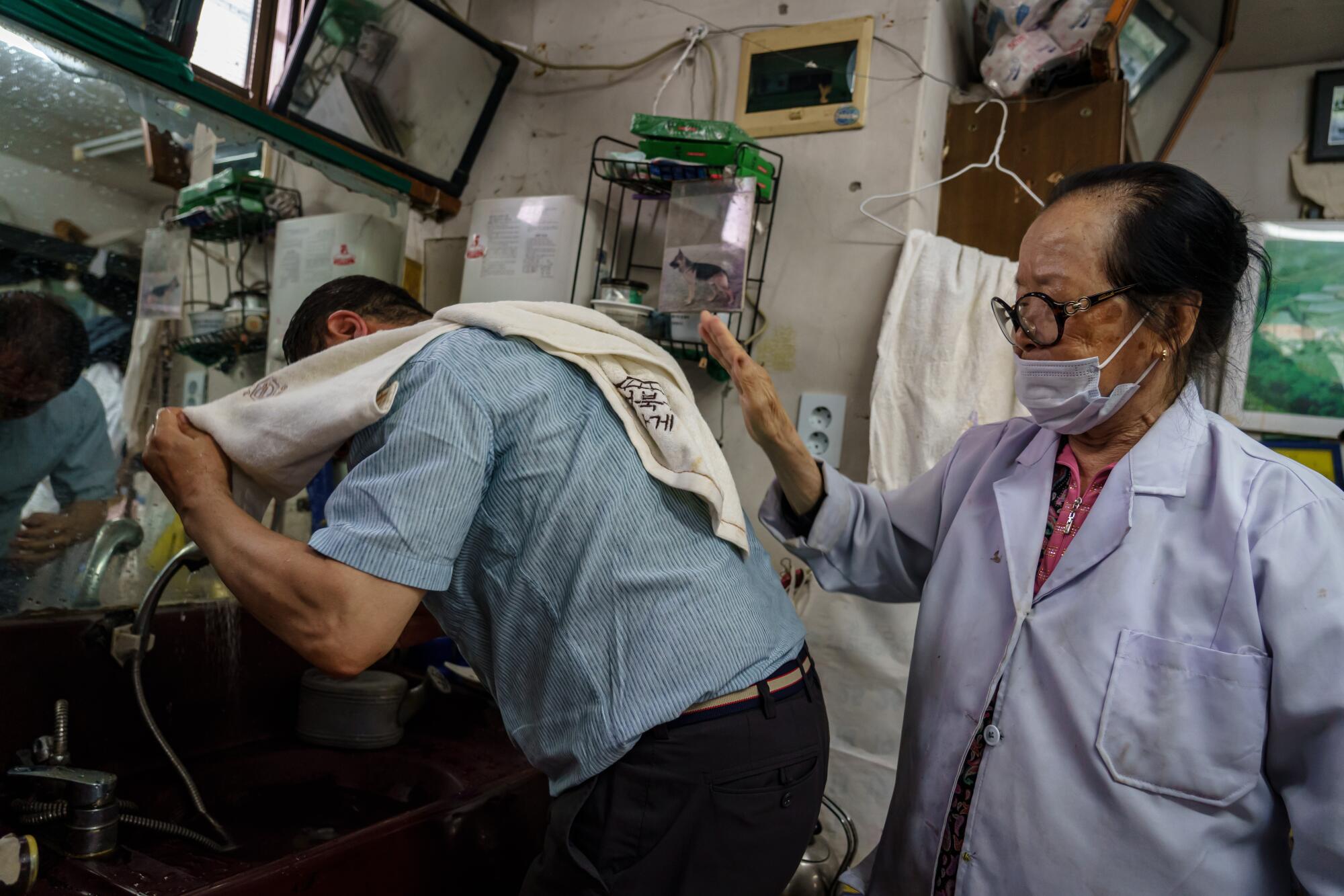 Barber Lee Duk-hoon gives customer a hand as he dries off after his haircut in Seoul