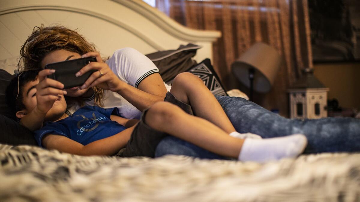 Andrea, 22, and her son Mateo, 4, watch videos on her phone in their Orange County home. She was a beneficiary of President Obama's Central American Minors Program, which the Trump administration ended in August, leaving her without legal protection.