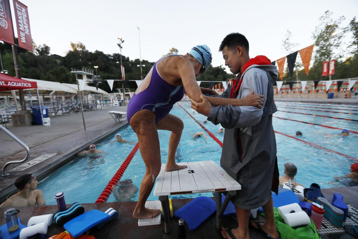Master swimmer Maurine Kornfeld, 97, gets a hand from one of her swim coaches, Andrew Lum, during practice at the Rose Bowl Aquatics Center in Pasadena.