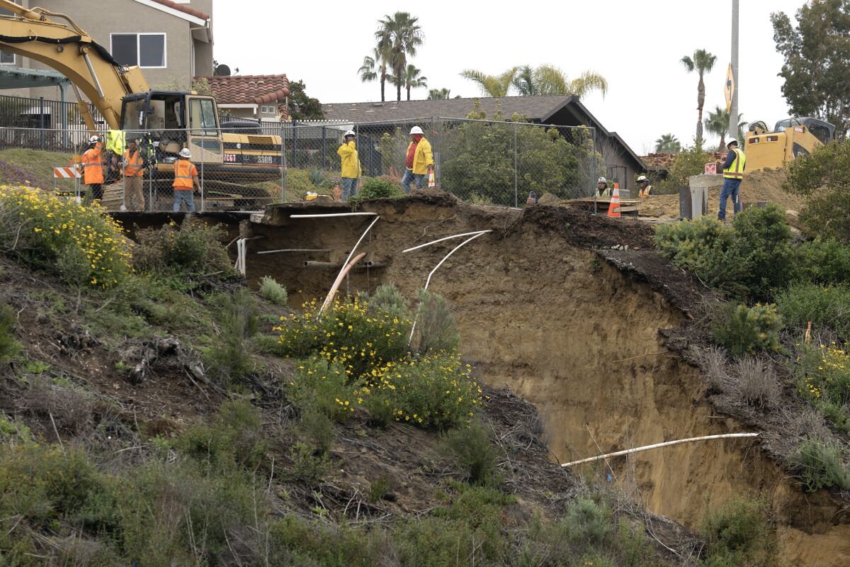 Workers stand near a sinkhole on Lake Drive in Encinitas on March 11