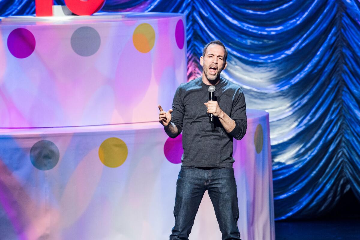 Bryan Callen holding a microphone onstage