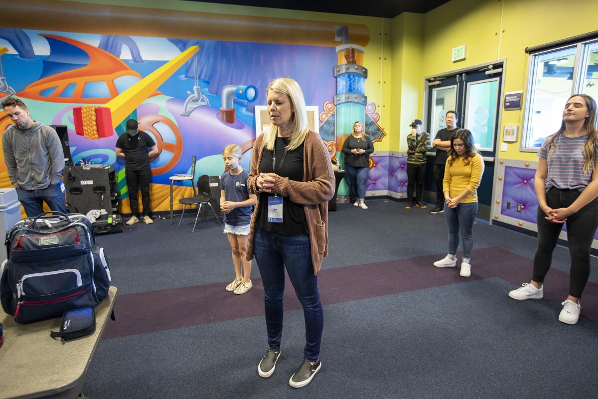 Jen Epperson, children's pastor at Mariners Church in Irvine, leads a prayer before recording a family worship service with other members.