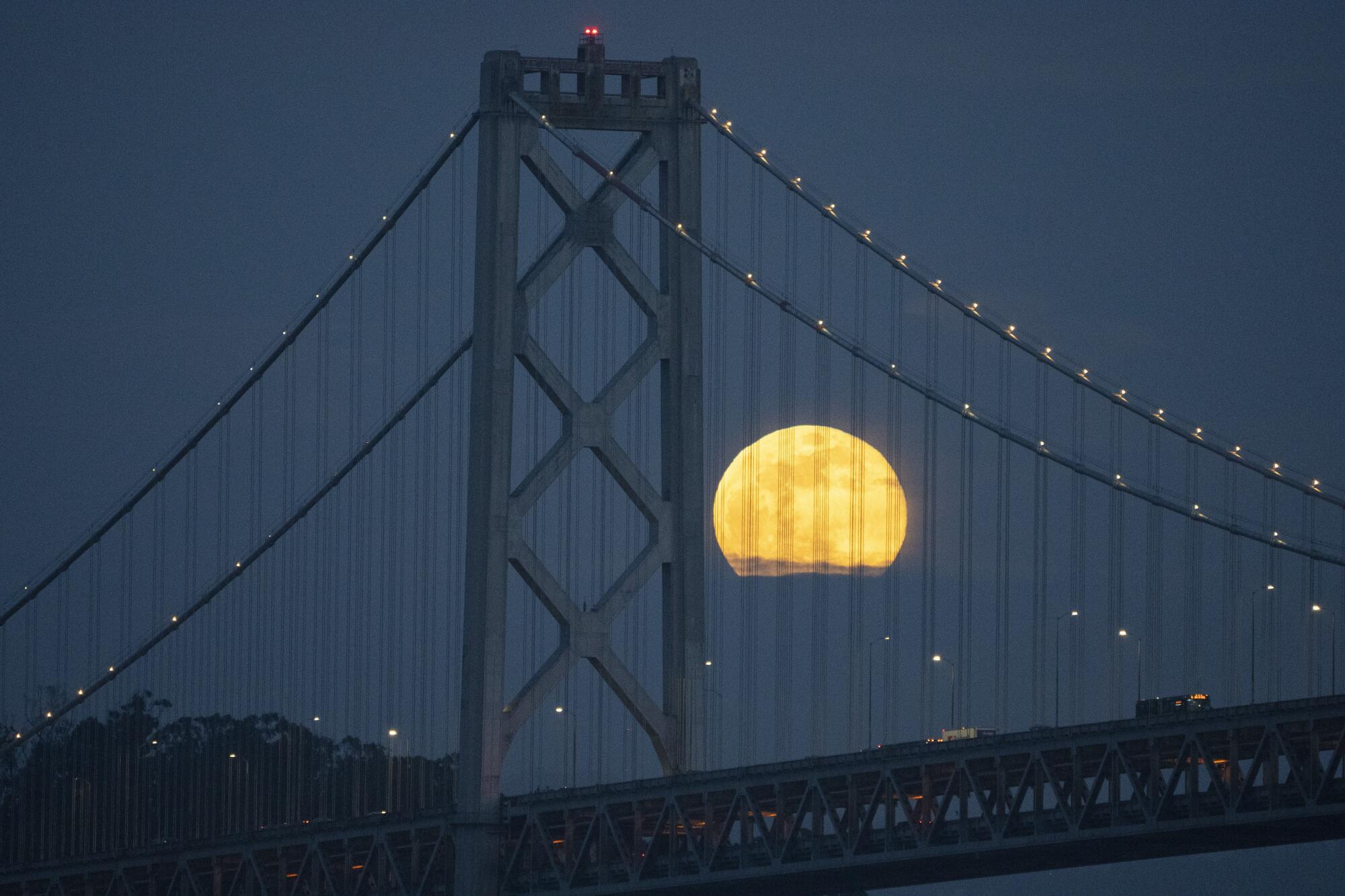 In January, a full moon rises over the San Francisco-Oakland Bay Bridge.