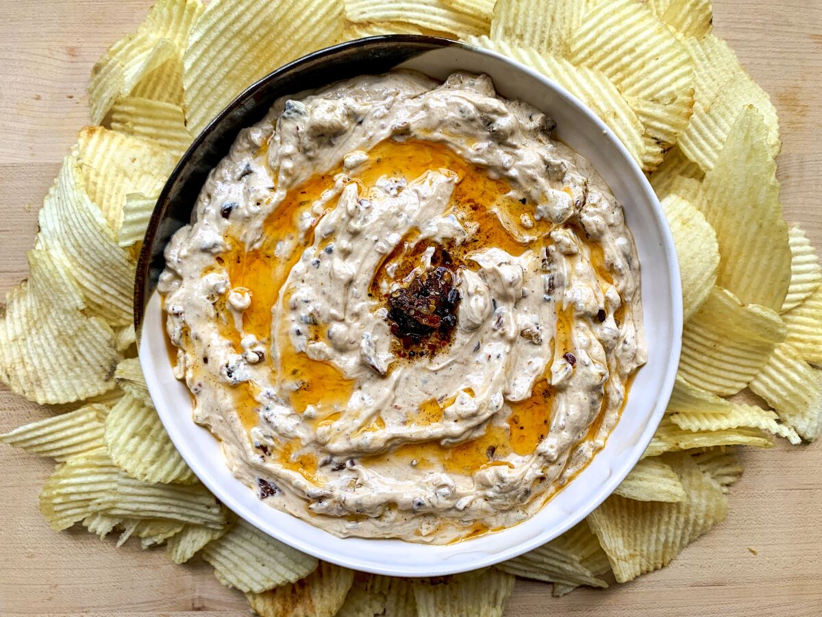 A round bowl of French onion-chili crisp dip surrounded by ruffled potato chips