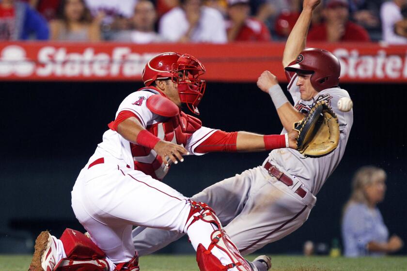 Angels catcher Carlos Perez takes the throw as Arizona's Nick Ahmed scores on a sacrifice fly in the ninth inning Monday night in Anaheim.