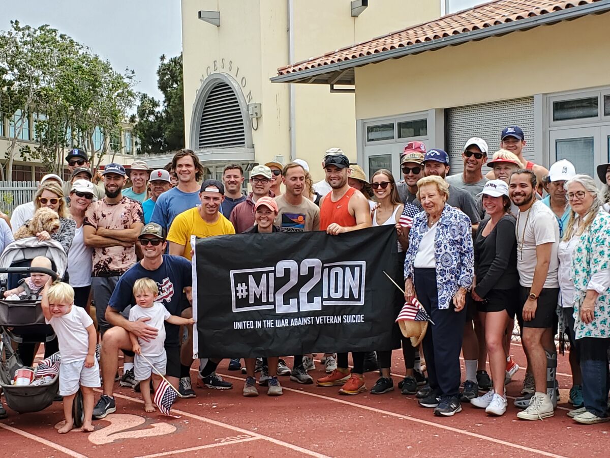 Dylan Walsh (in orange) greets his supporters after completing a 100-mile run around the La Jolla High School track.