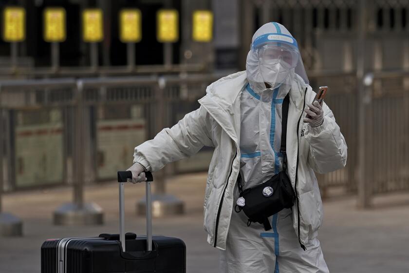 A woman wearing a protective gear to help curb the spread of the coronavirus walks with her luggage arrives to the railway station to catch her train in Beijing, Wednesday, Jan. 27, 2021. China has given more than 22 million COVID vaccine shots to date as it carries out a drive ahead of next month's Lunar New Year holiday, health authorities said Wednesday. (AP Photo/Andy Wong)