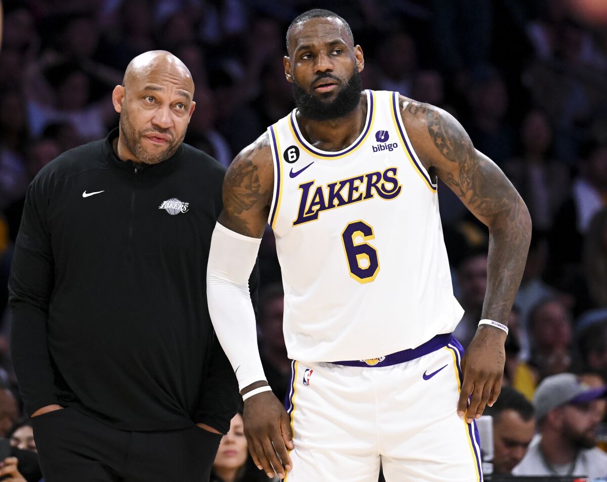 Lakers forveti LeBron James, sağda, oyun molası sırasında yan çizgide baş antrenör Darvin Ham ile konuşuyor.