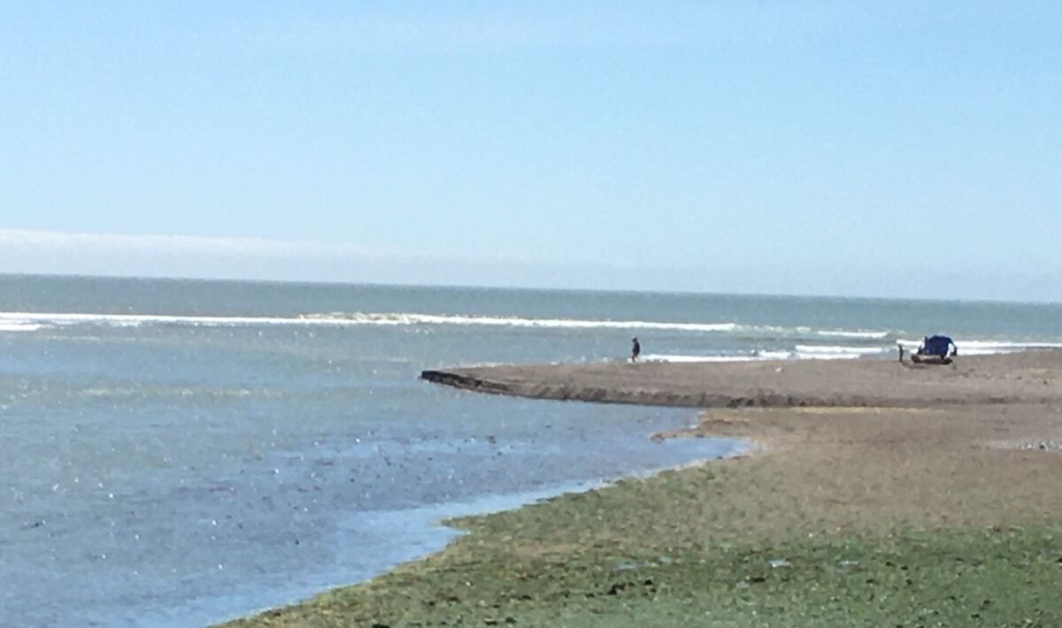 A lone beachgoer walks near the waves in Bolinas, Calif.