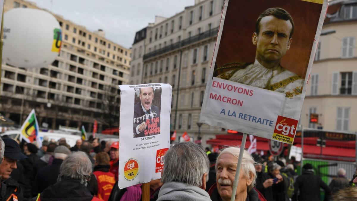 A demonstrator holds a placard reading "Send Macron on retirement!" in Paris on Dec. 18, 2018, one of many protests targeting French President Emmanuel Macron.