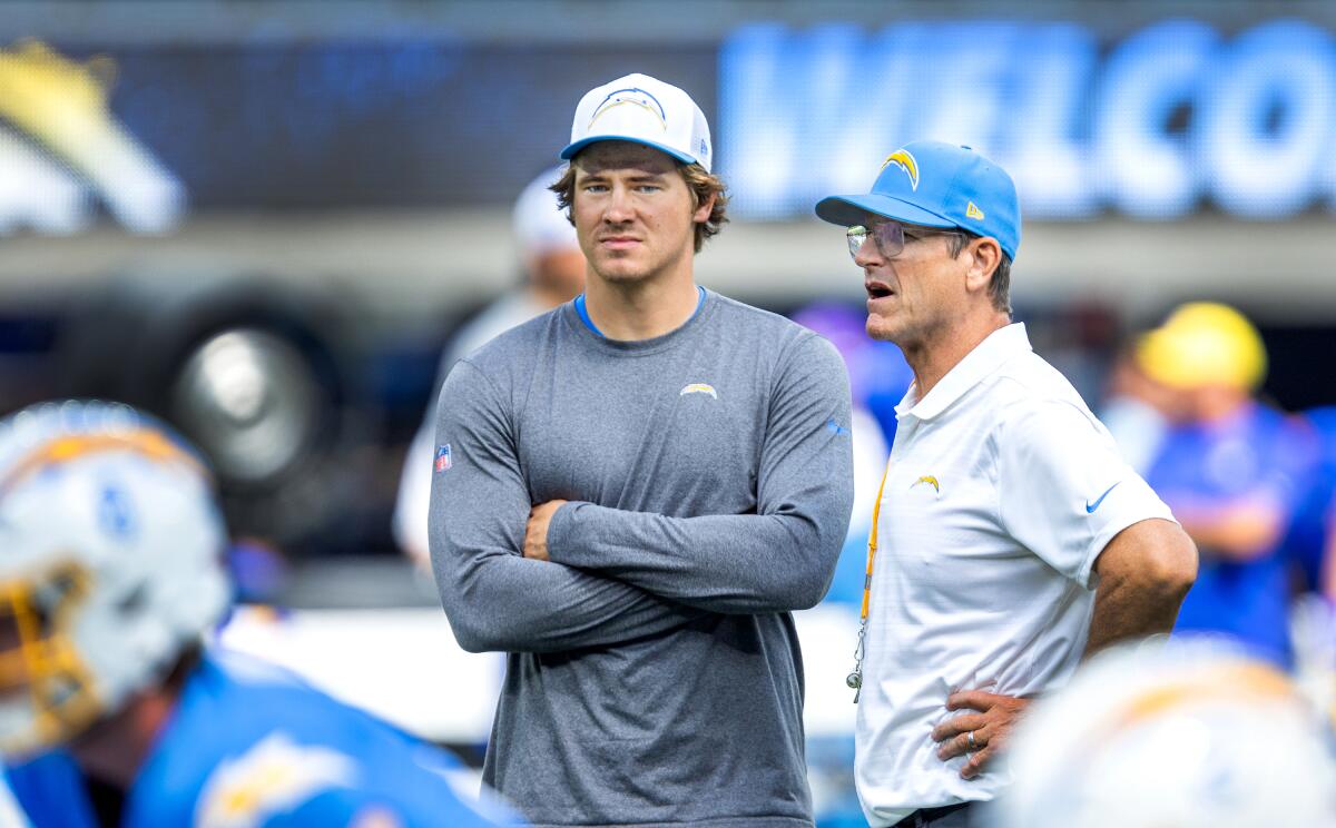 Chargers quarterback Justin Herbert, left, and coach Jim Harbaugh speak before a preseason game against the Rams on Aug. 17.