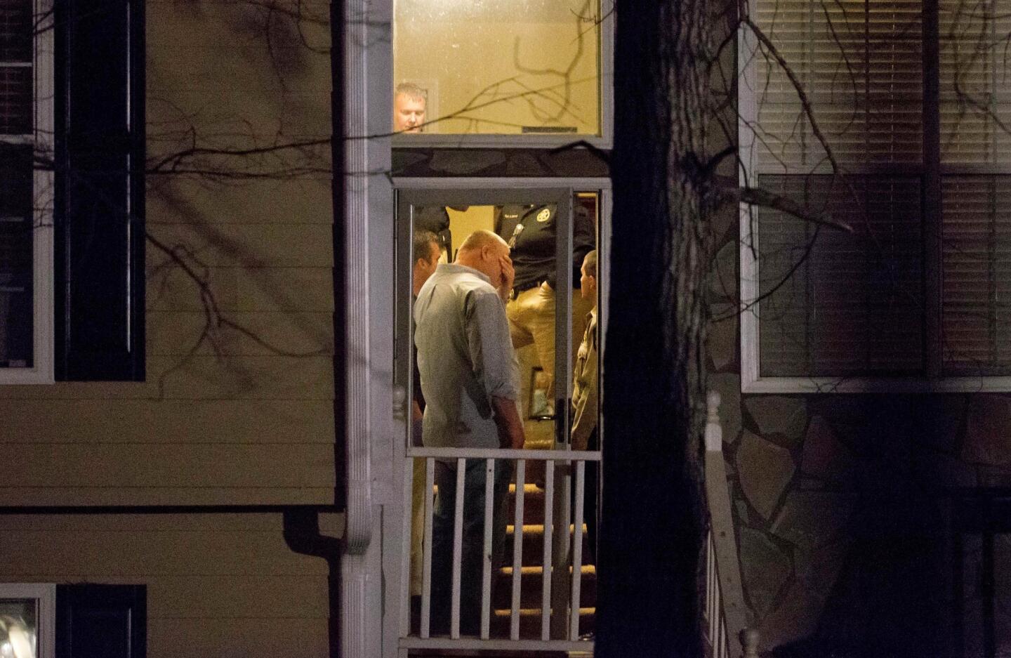Police stand in the doorway of a home while investigating the shooting scene where authorities say five people are dead, including the gunman, in Douglasville, Ga.