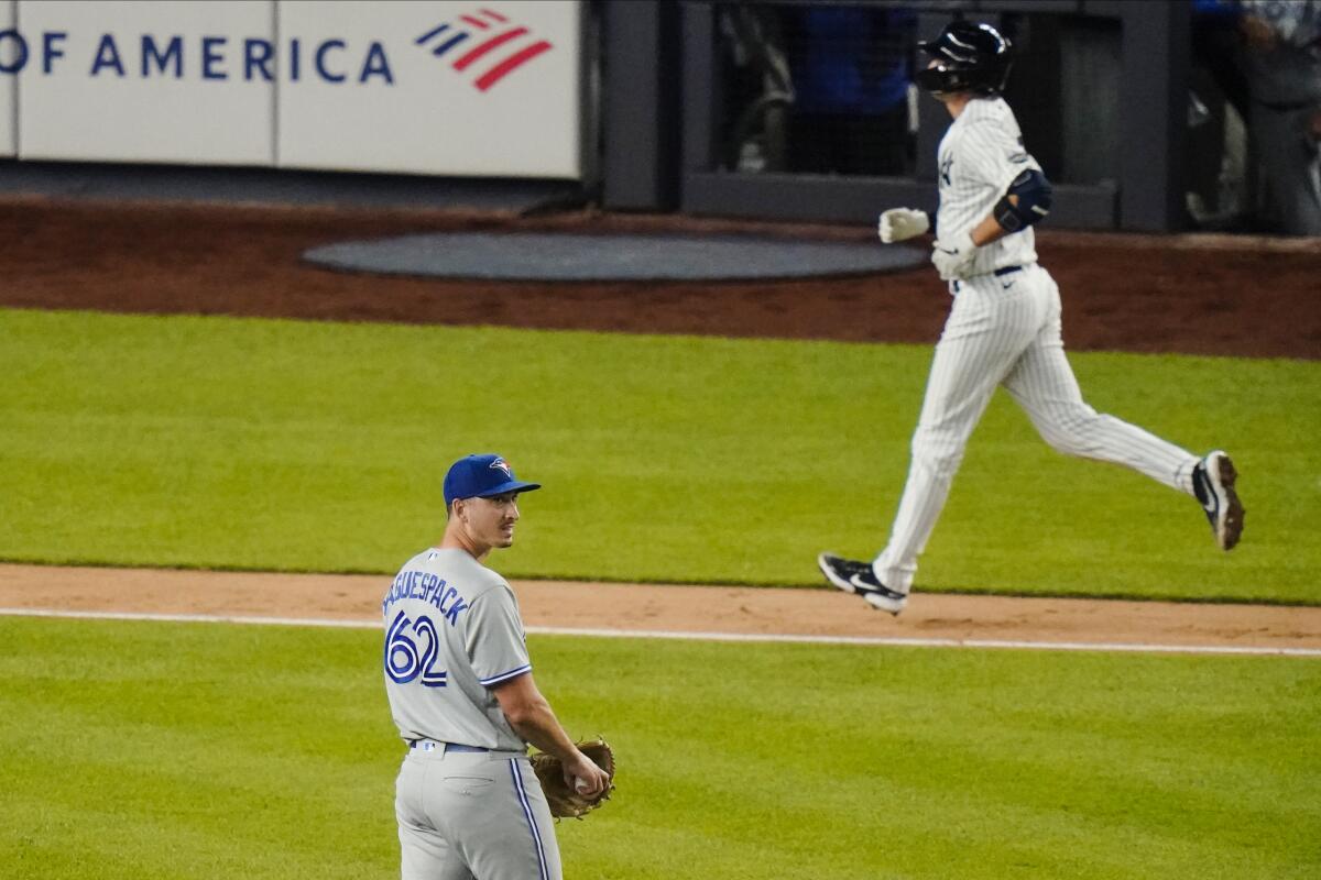 Toronto Blue Jays' Jacob Waguespack reacts as New York Yankees' Kyle Higashioka runs the bases after hitting a home run.