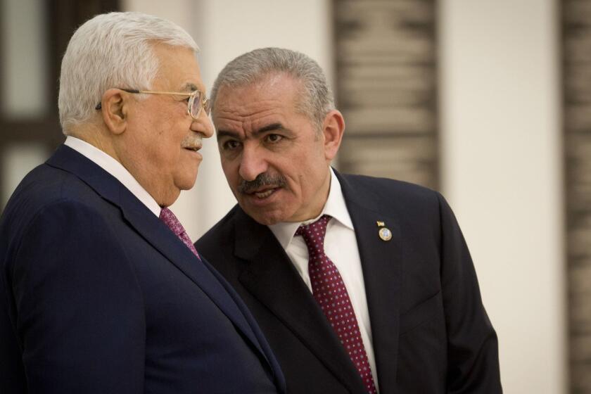 Palestinian Prime Minister Mohammad Ishtayeh, right, talks with Palestinian President Mahmoud Abbas during a swearing in of the new government in the West Bank city of Ramallah, Saturday, April 13, 2019.(AP Photo/Majdi Mohammed)
