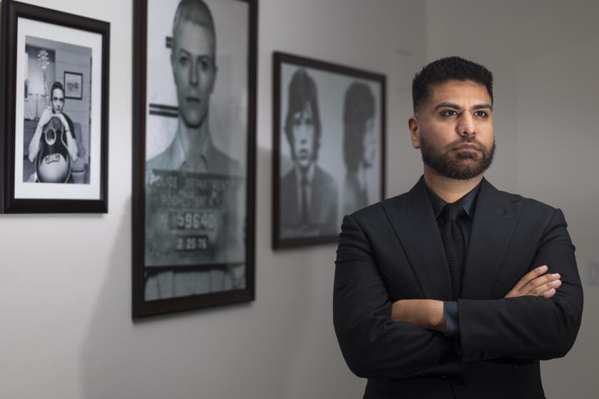 Pasadena, CA - July 15: Damon Alimouri,33, stands in front of photographs of musicians he looks up to in his law office in Pasadena, CA on Monday, July 15, 2024. (Zoe Cranfill / Los Angeles Times)