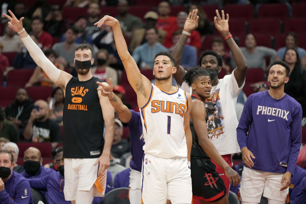 Phoenix Suns guard Devin Booker (1) watches his three-point shot-attempt during the second half of an NBA basketball game against the Houston Rockets, Sunday, Nov. 14, 2021, in Houston. (AP Photo/Eric Christian Smith)